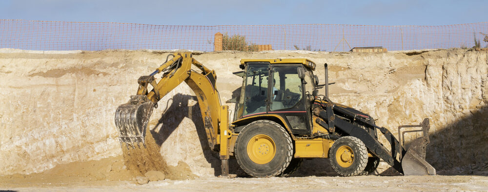 Backhoe loader excavating sand at an active construction site in Naples, Florida