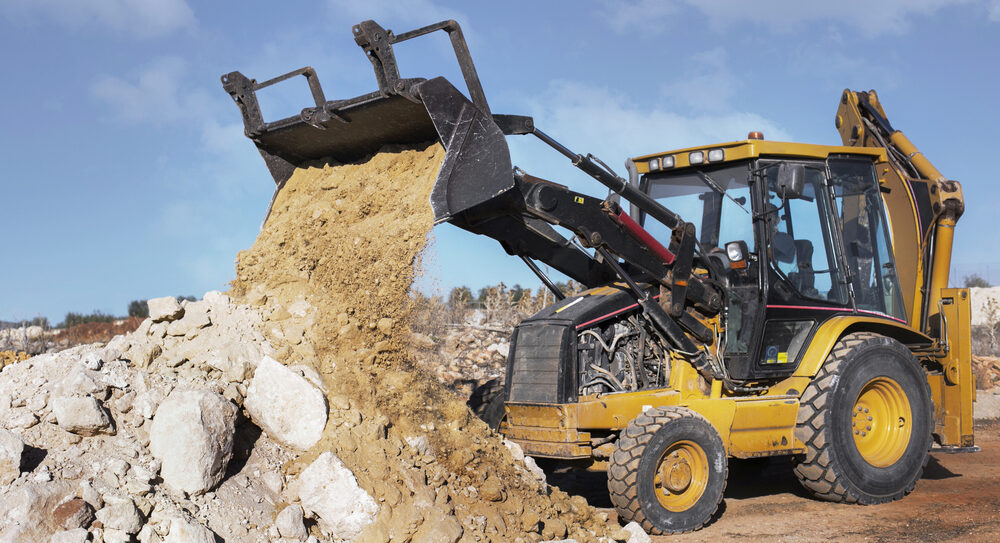 Excavator operating at a dusty construction site in Odessa, TX