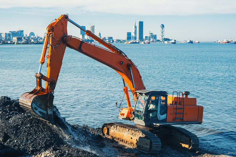 Excavator removing wet soil near a waterfront construction site in Naples, Florida