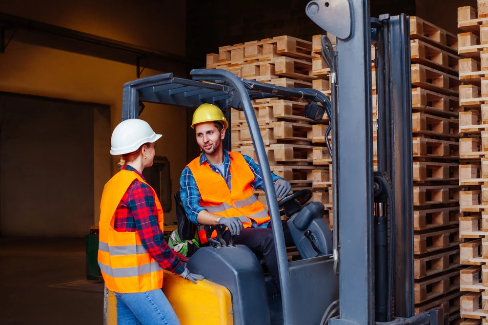 Workers using a telehandler to move materials on a construction site in Corpus Christi, Texas