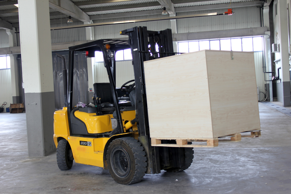 Yellow forklift moving a large wooden crate inside a warehouse facility in Naples, Florida
