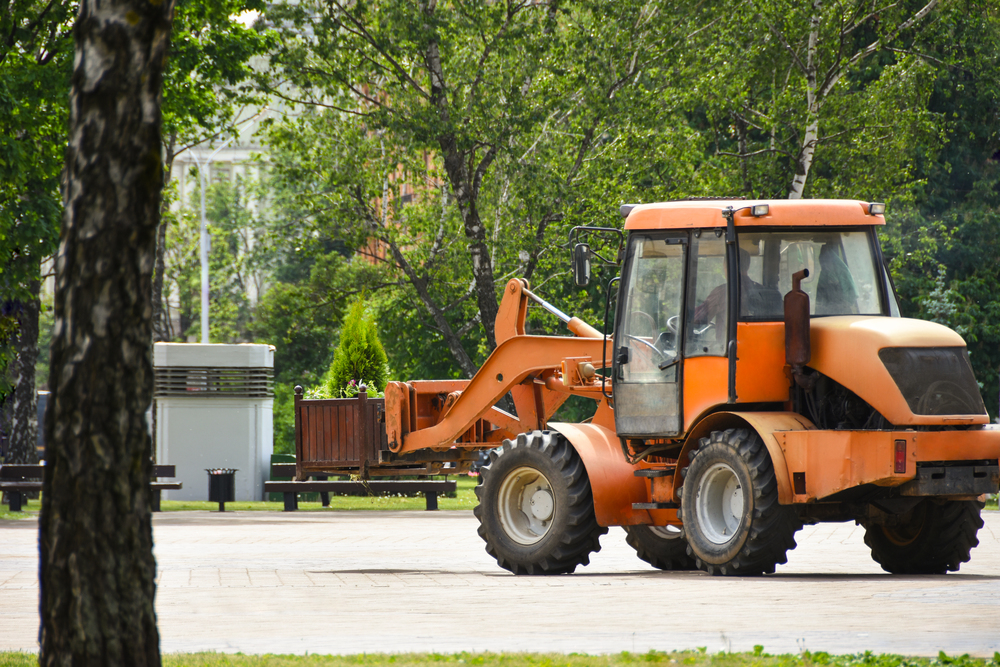 Compact wheel loader operating in an urban park area in Collinsville, IL, performing light construction or landscaping work.