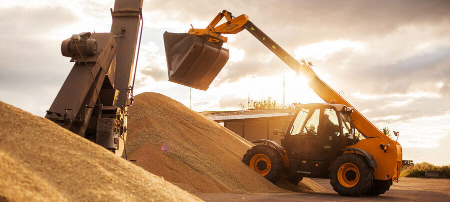 Telehandler loading bulk construction material into a hopper at a job site in Banning, CA.