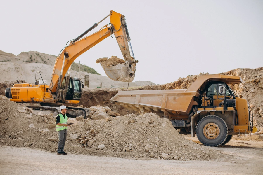 Male worker operating a bulldozer in a sand quarry
