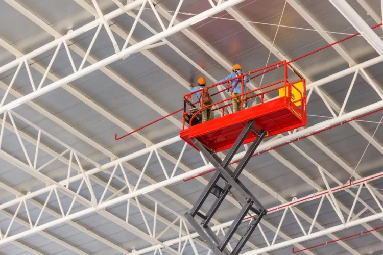 Two men working on a lift in a large building.
