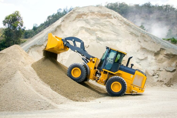 A large yellow wheel loader is working on a pile of sand.