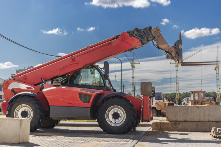 Telehandlers lifting pallets at a commercial construction site in the U.S.