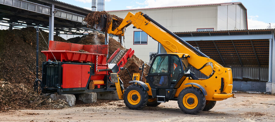 Telescopic boom of a telehandler extending upward at a building site. 