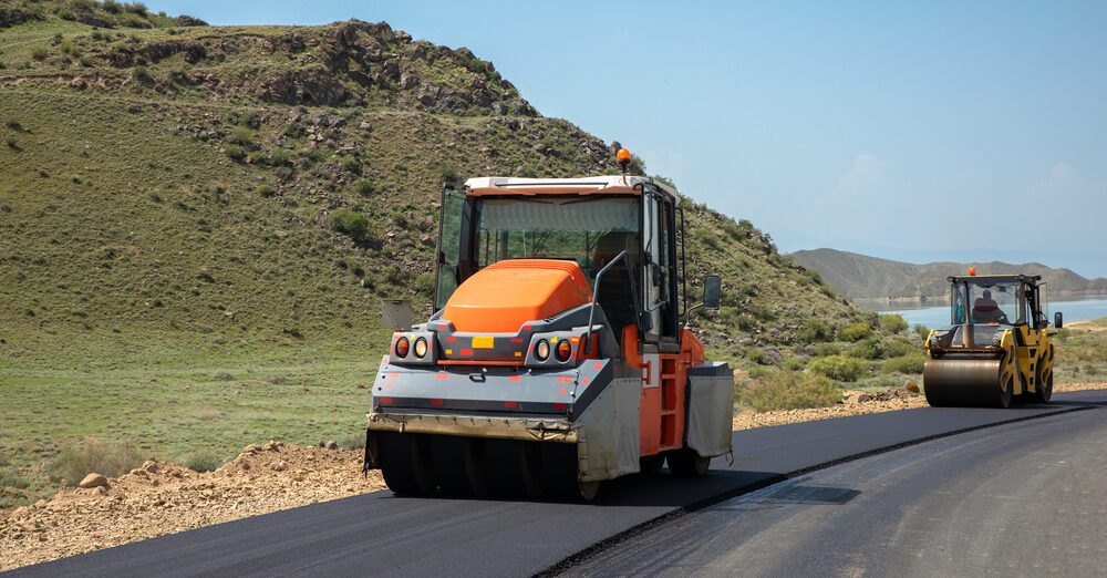 Construction worker operating a road roller during peak summer season at a job site in USA